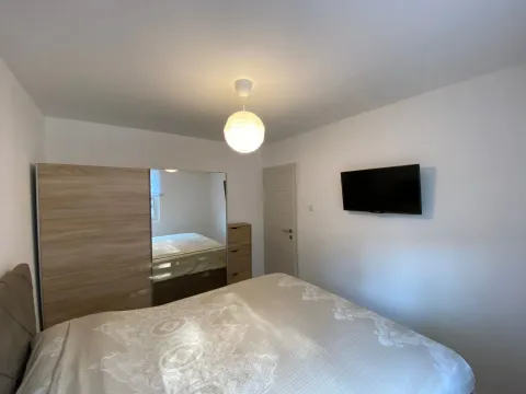Furnished bedroom with a double bed, wardrobe, and wall-mounted TV. - image 15