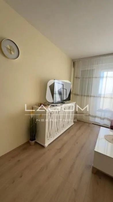 Dnevna soba sa TV komodom i drvenim podom.