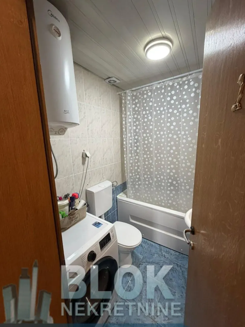 Smaller bathroom with a bathtub, toilet, and washing machine.