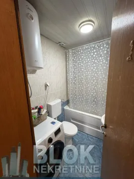 Smaller bathroom with a bathtub, toilet, and washing machine. - image 12