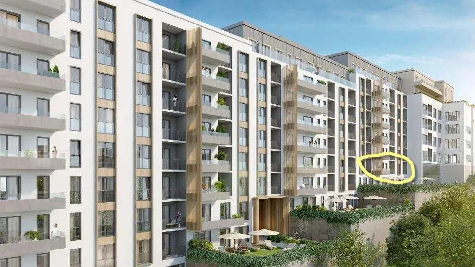 Exterior view of a modern residential building with balconies and a landscaped courtyard.