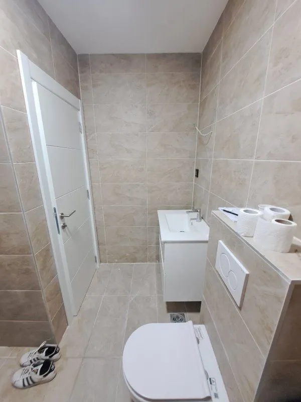Pogled na moderno opremljeno kupatilo sa umivaonikom i toaletom u bež pločicama.