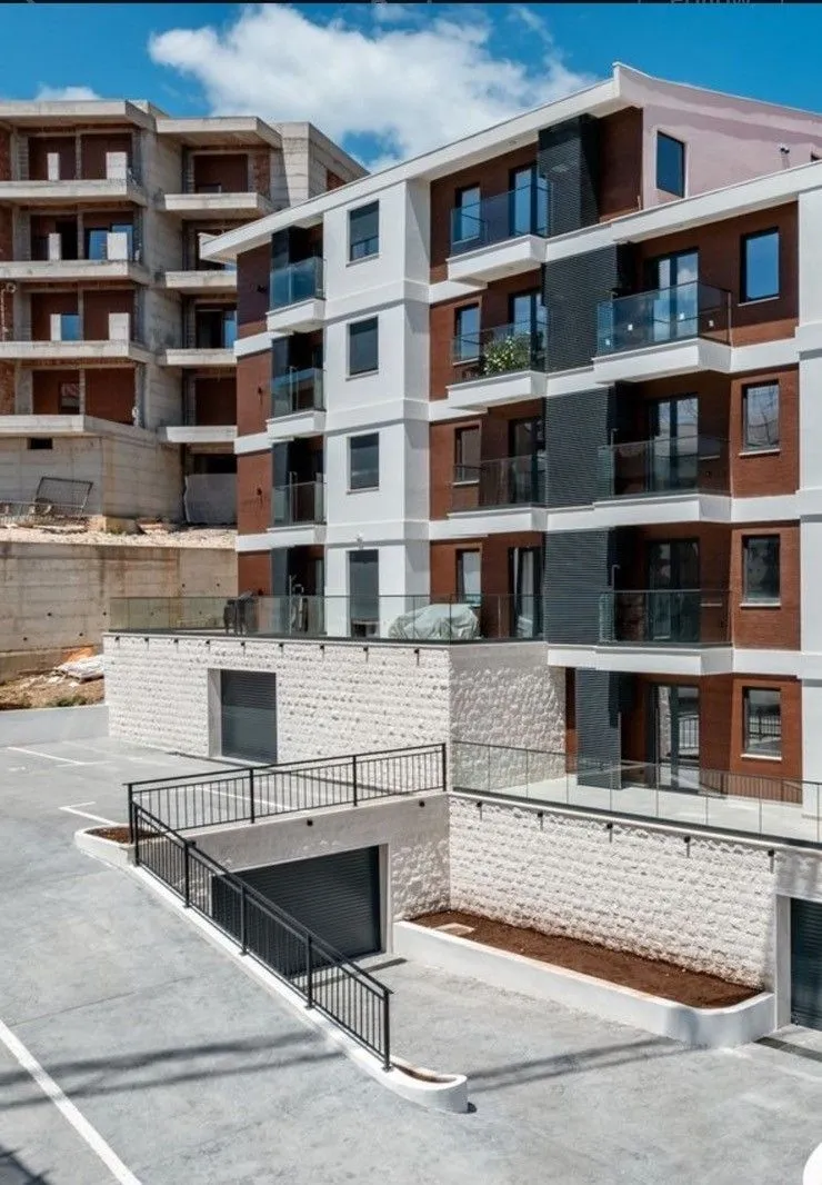 Moderna novoizgrađena stambena zgrada sa garažnim prilazom.