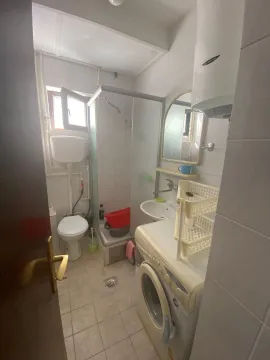 Small bathroom with a shower cabin, washbasin, toilet, and washing machine. - image 6