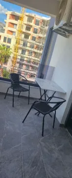 Furnished balcony with a table, chairs, and a view of a building under construction. - image 9