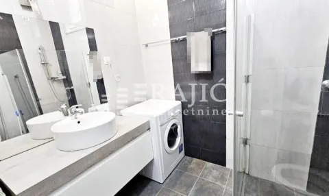 Modern bathroom with a sink, shower cabin, and washing machine. - image 9