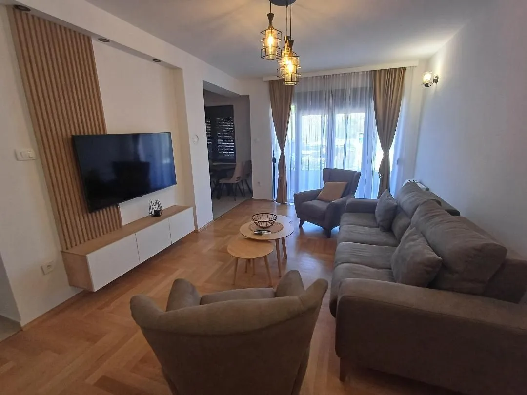 Spacious living room with a sofa set, TV, and dining area in the background.