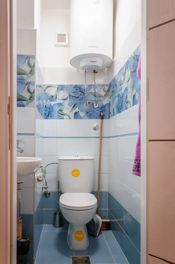 Small bathroom with a toilet, sink, and water heater.
