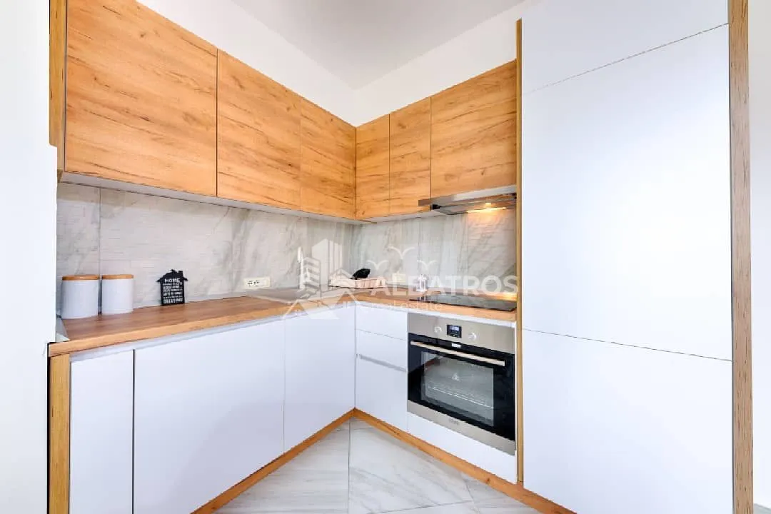 Modern kitchen with white units and wooden details.