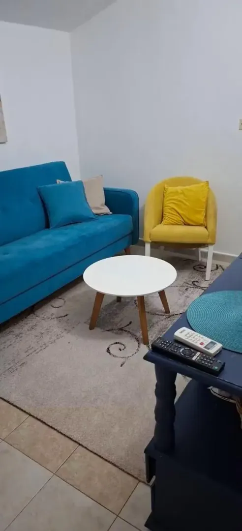 Living room with a blue sofa, yellow armchair, and a small table.