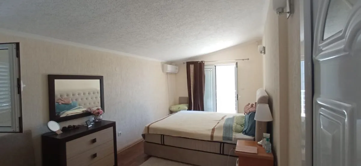 Furnished bedroom with a double bed, dresser, and mirror.