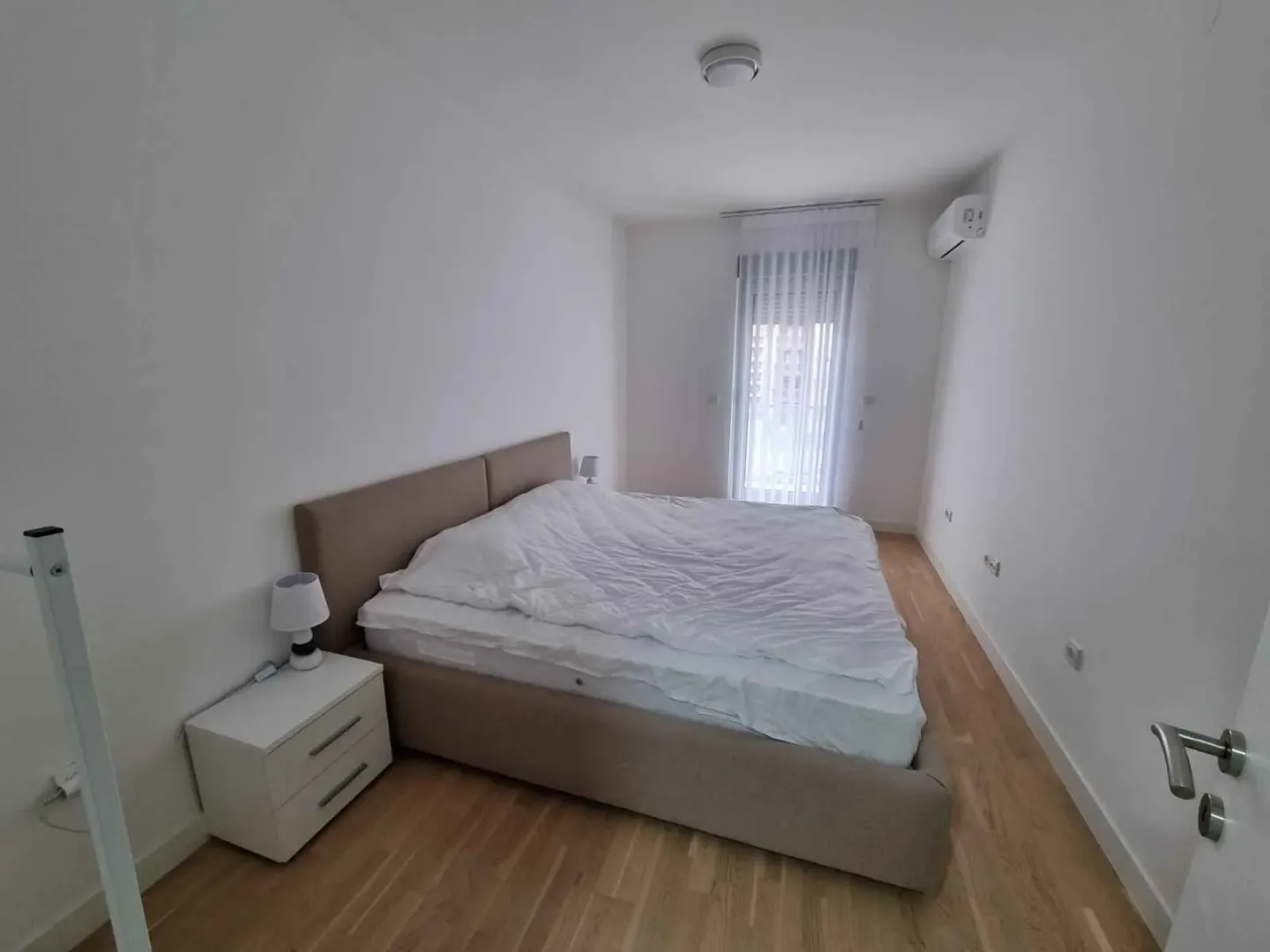 Spavaća soba sa bračnim krevetom i noćnim stočićem.