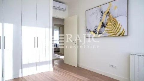 Bedroom with a built-in wardrobe, a large wall painting, and laminate flooring. - image 5