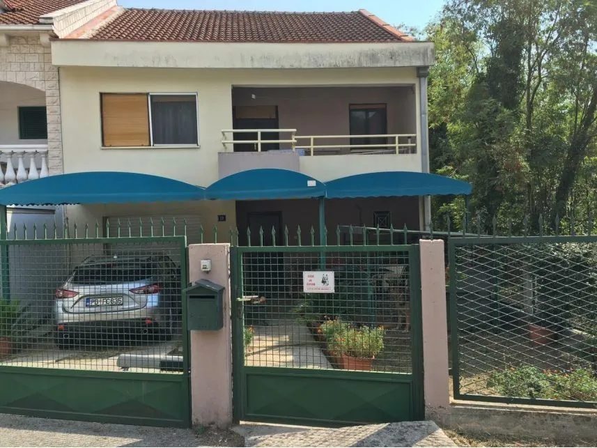 Dvospratna kuća sa ograđenim dvorištem i parking mjestom.