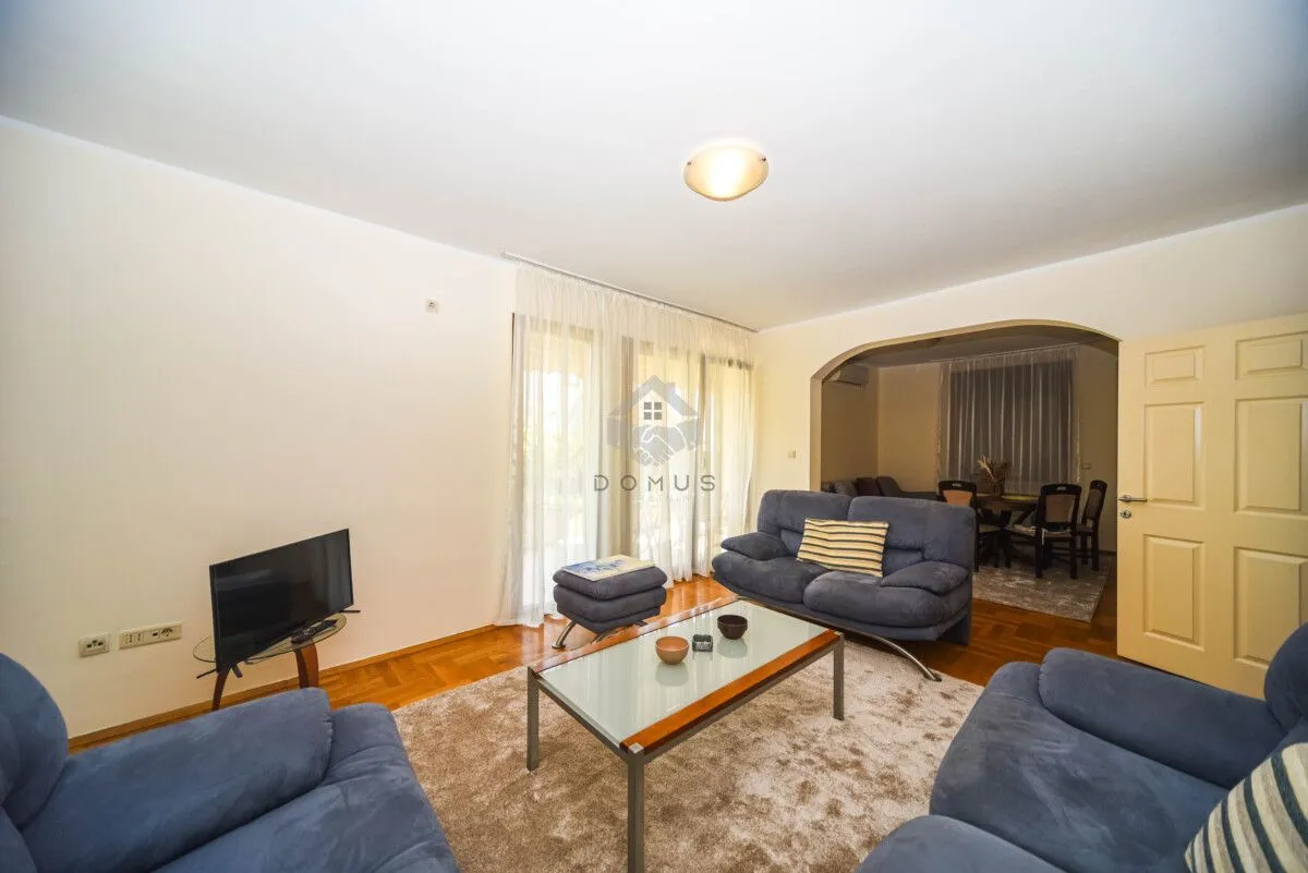 Living room with sofa set, coffee table and TV, with a view of the dining area.