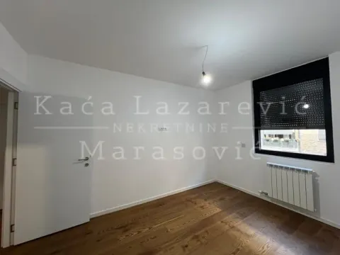 Prazna soba sa drvenim podom, belim zidovima i prozorom sa roletnama. - image 9