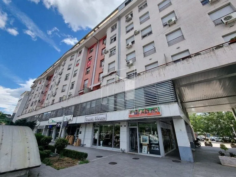 Pogled na spoljašnjost stambene zgrade sa poslovnim prostorima u prizemlju.