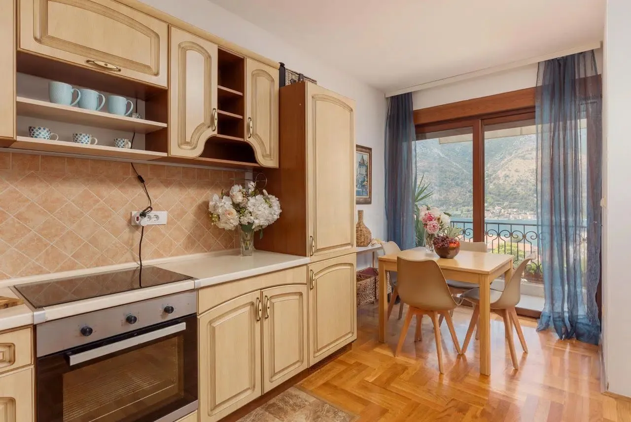 Dining area and kitchen with wooden cabinets and a sea view.