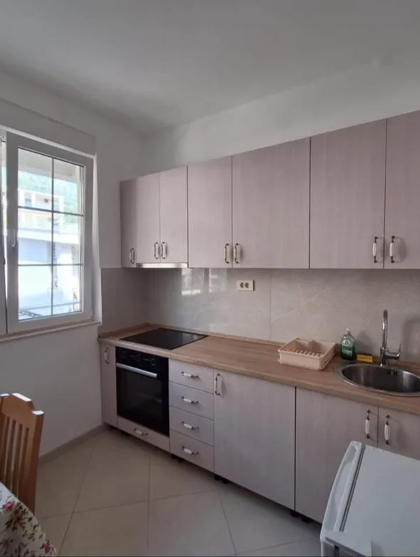 Small bright kitchen with wooden cabinets and built-in appliances.