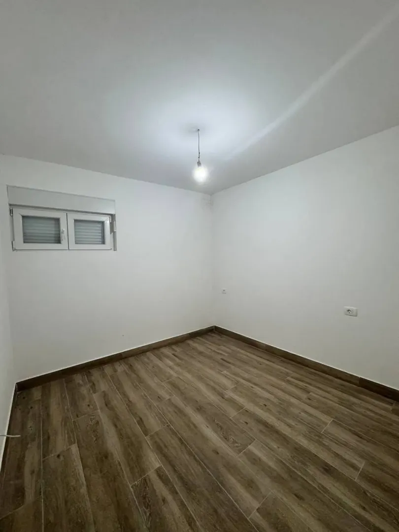 Prazna soba sa bijelim zidovima i drvenim podom.