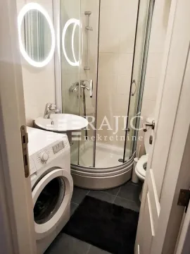 Smaller bathroom with a shower cabin, sink, and washing machine. - image 4