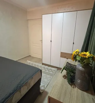 Bedroom with a bed, large wardrobe, and chest of drawers with a vase of flowers. - image 5