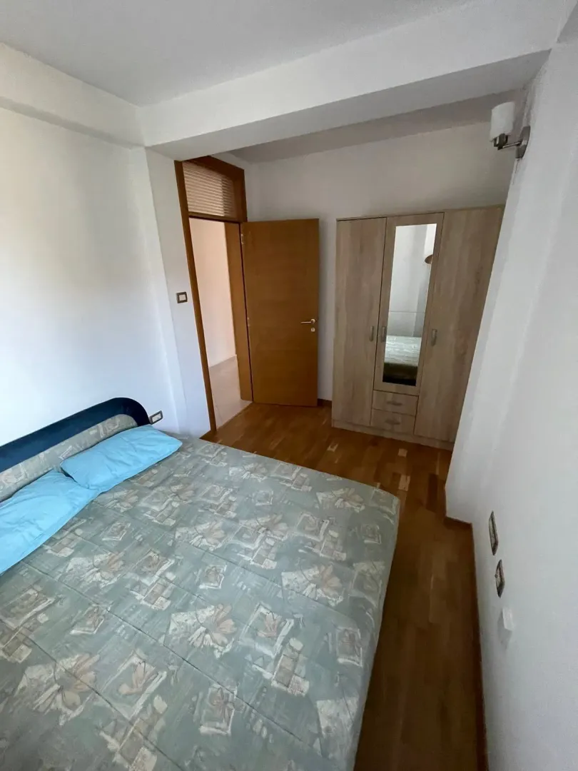 Furnished bedroom with a double bed and a wooden wardrobe.