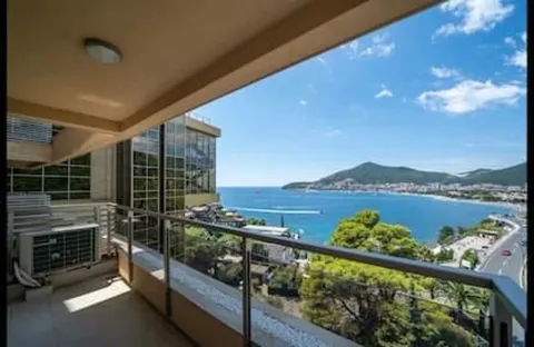 Covered balcony with a metal railing and a view of the sea and coast. - image 12