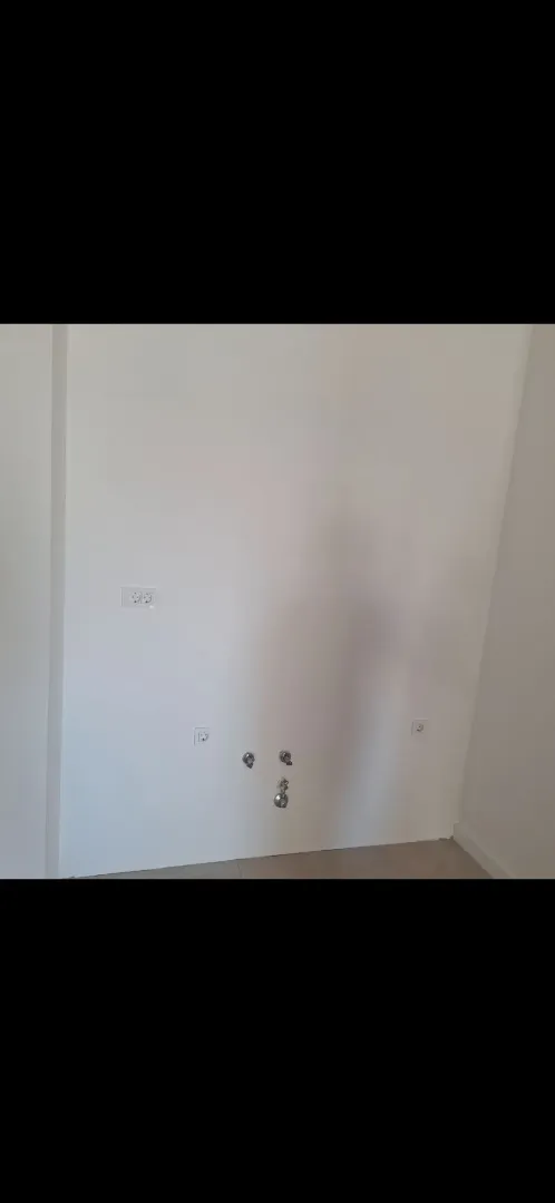 Prikaz priključaka za vodu i struju na bijelom zidu u prostoriji.