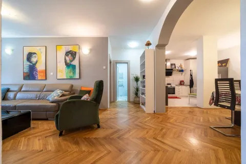 Spacious living room with parquet flooring, a leather sofa, and an archway leading to the kitchen. - image 30