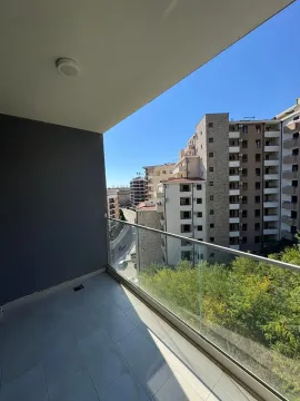 Nenamješten balkon sa staklenom ogradom i pogledom na grad. - image 2