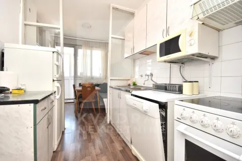 Compact kitchen with white cabinets and appliances, with a view of the dining area in the background. - image 4