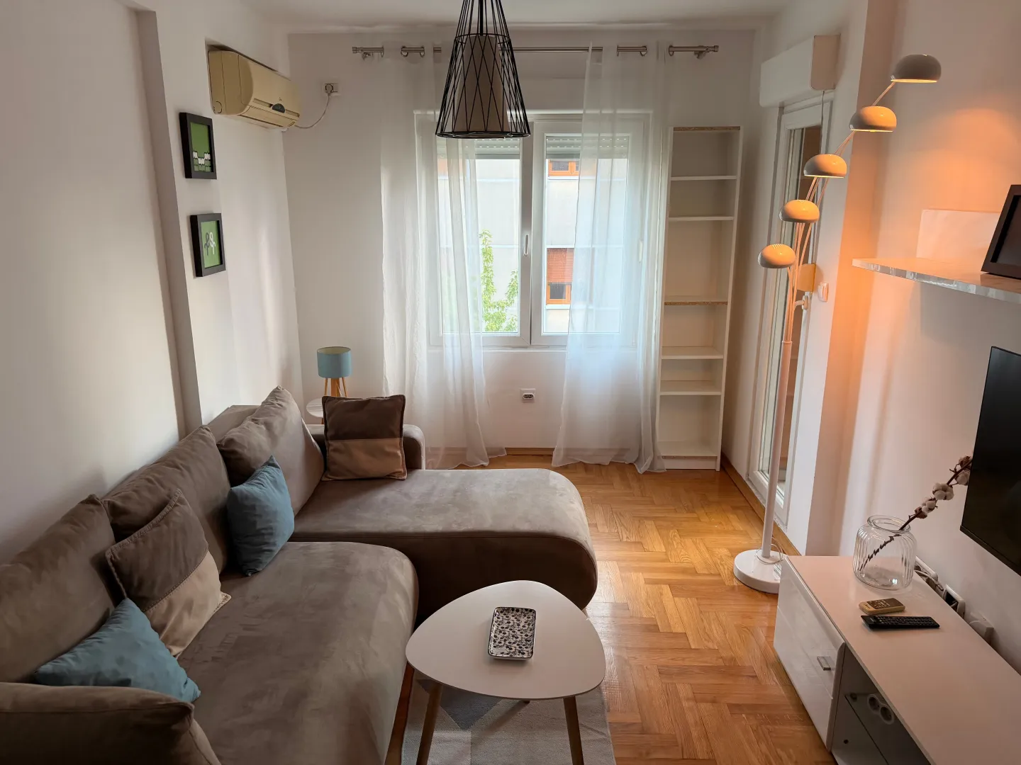 Comfortable living room with a sectional sofa and parquet flooring.