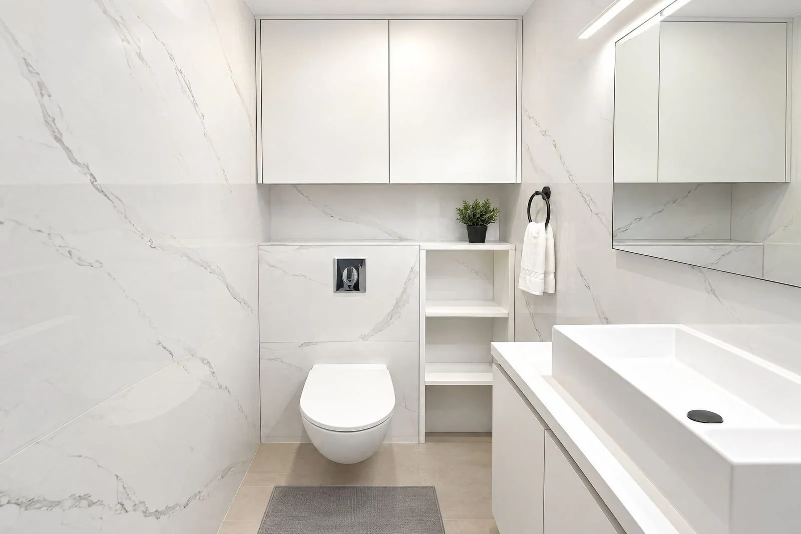 Modernly equipped bathroom with white ceramic tiles and built-in sanitaryware.