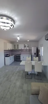 Modern kitchen with white cabinetry and a dining table. - image 6