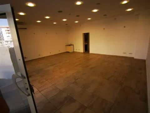A spacious empty room with tiled floors and recessed ceiling lights. - image 3