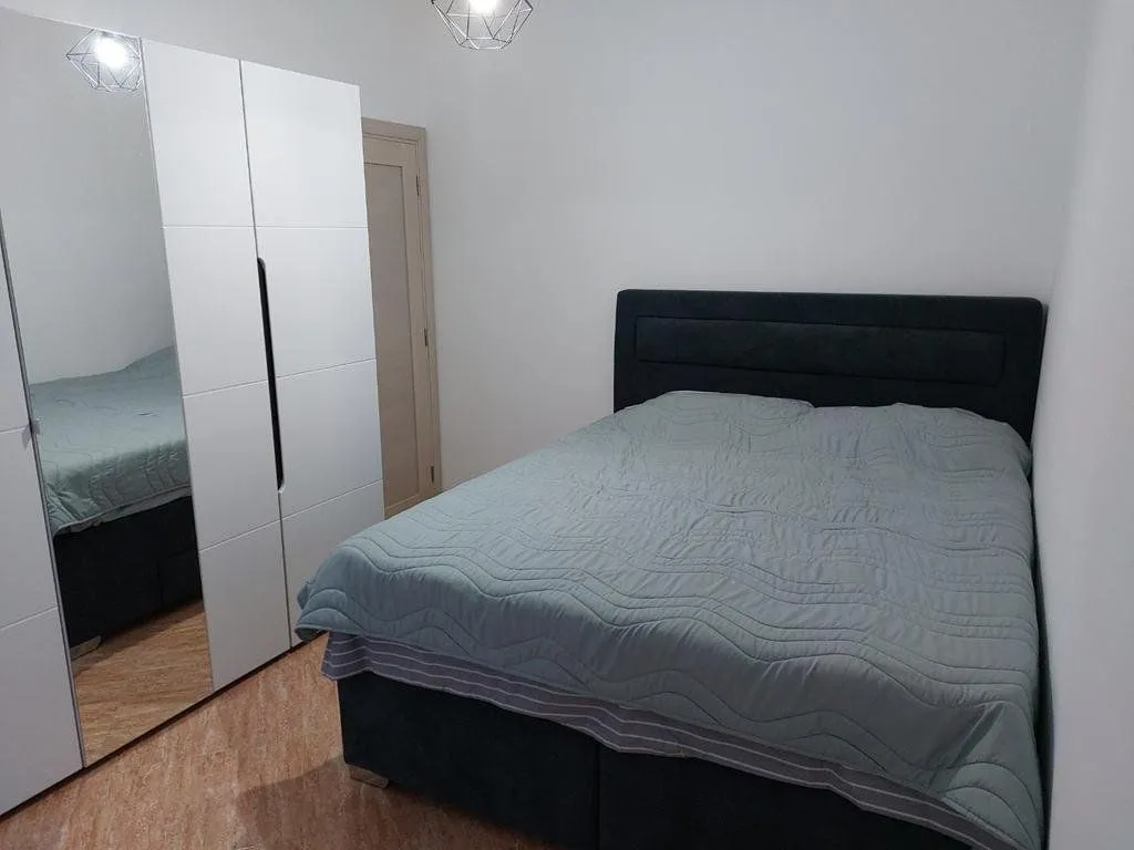 Furnished bedroom with a double bed and a white wardrobe with a mirror.