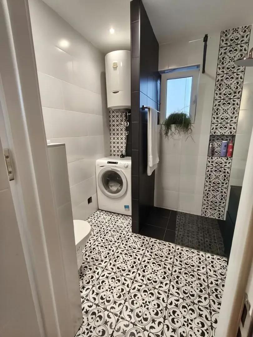 Moderno opremljeno kupatilo sa tuš kabinom, veš mašinom i bojlerom.