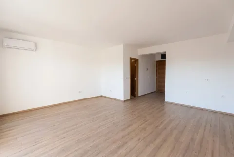 Empty living room with laminate flooring and an air conditioner. - image 2