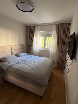 Namještena spavaća soba sa bračnim krevetom, prozorom i TV-om na zidu. - image 4