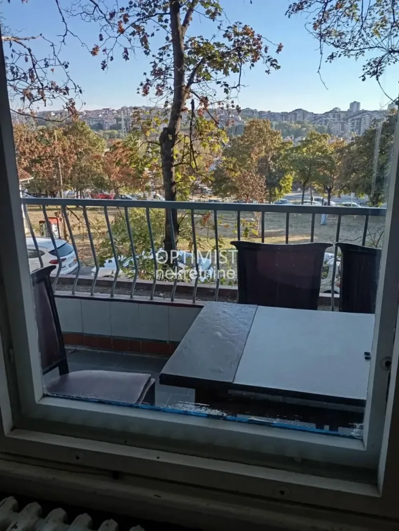 Pogled na terasu sa garniturom za sedenje kroz prozor.