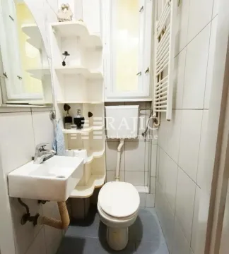 Smaller bathroom with a sink, toilet, and shelving. - image 11