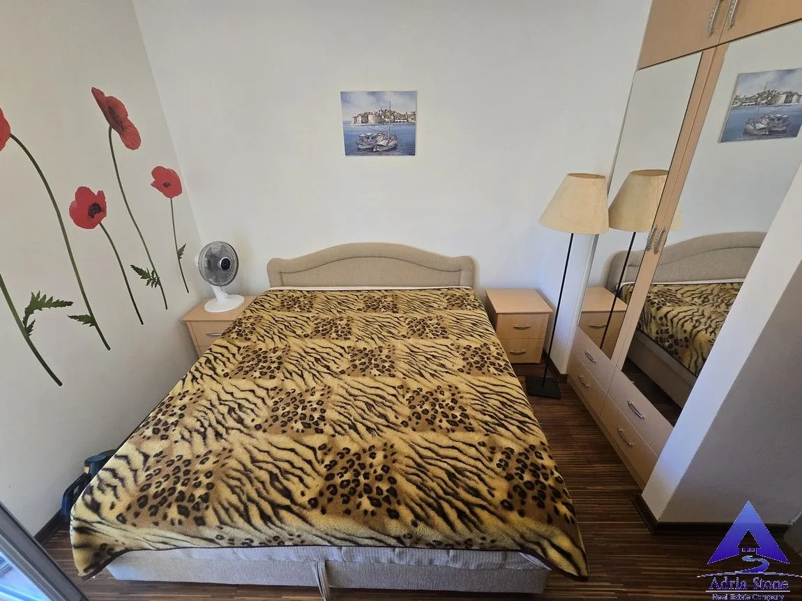 Namještena spavaća soba sa bračnim krevetom, ormarom i noćnim stočićima.