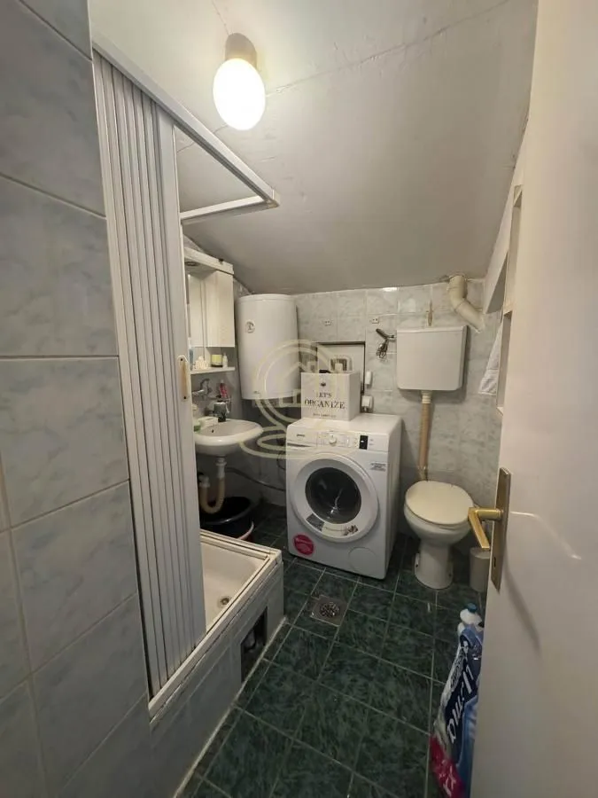 Manje kupatilo sa tuš kabinom, umivaonikom, WC šoljom i veš mašinom.