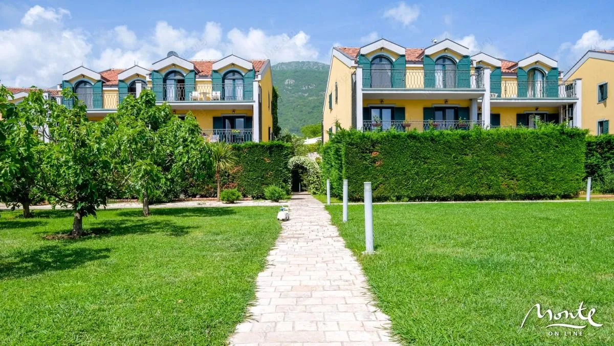 Pogled na spoljašnjost zgrade sa uređenim dvorištem i travnjakom.