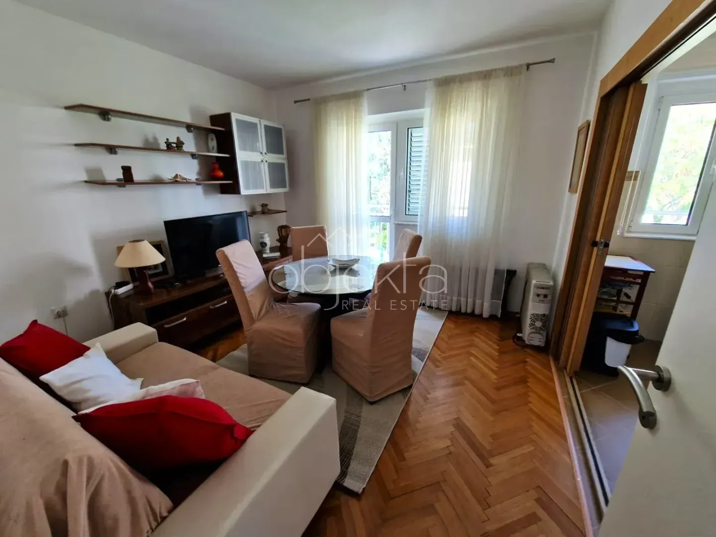 Living room with sofa, TV unit and dining table.