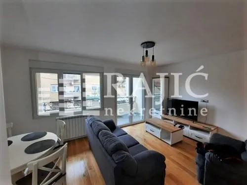 Living room with sofa, dining table, and TV unit.