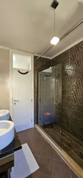 Modern bathroom with a walk-in shower and two sinks. - image 6