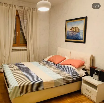 Uređena spavaća soba sa bračnim krevetom, bijelim zavjesama i umjetničkom slikom na zidu. - image 6