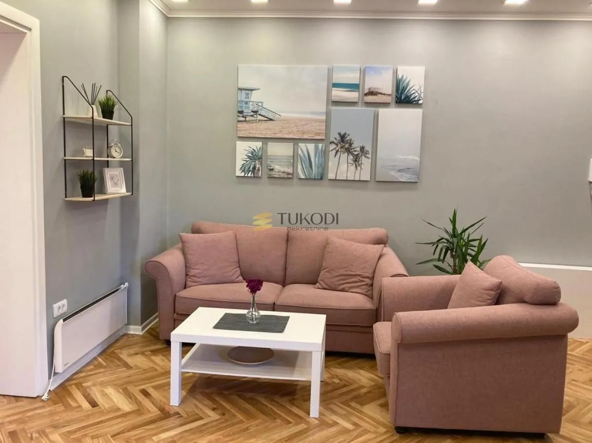 Living room with a pink sofa set, a white coffee table, and parquet flooring.